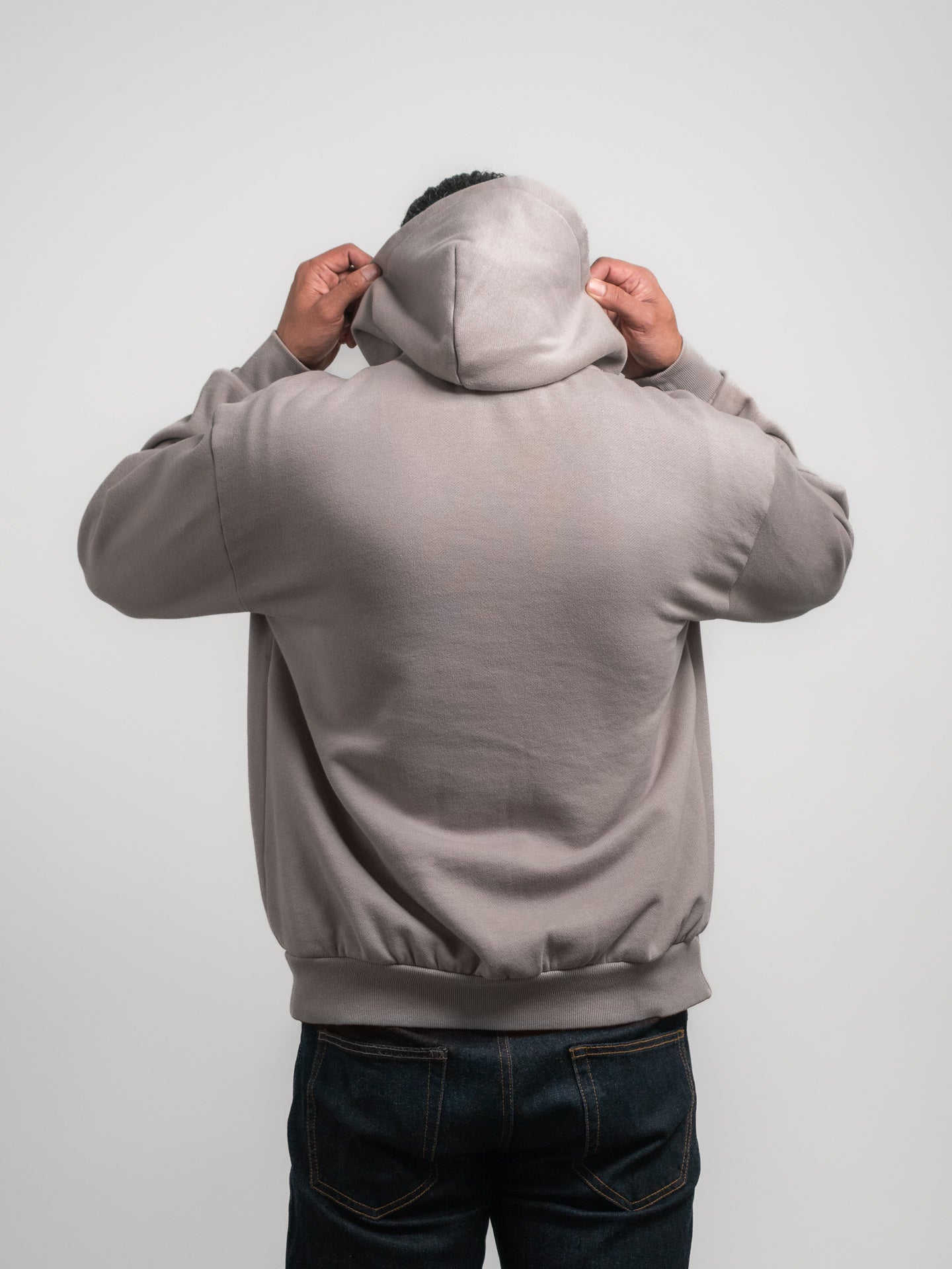 Person wearing a gray SecondHand Kids "Out of Place" hoodie with the back to the camera on a light gray background