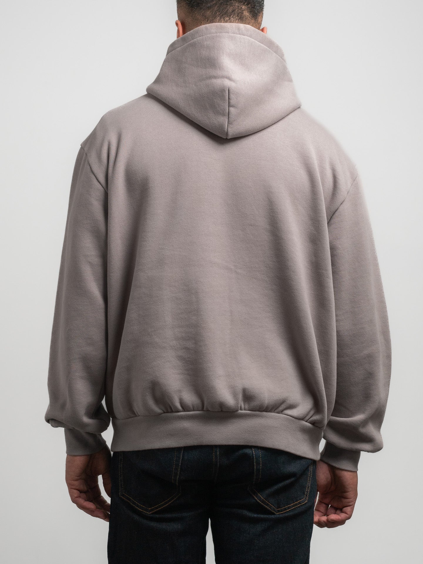 Person wearing a grey SecondHand Kids hoodie from behind on a plain background